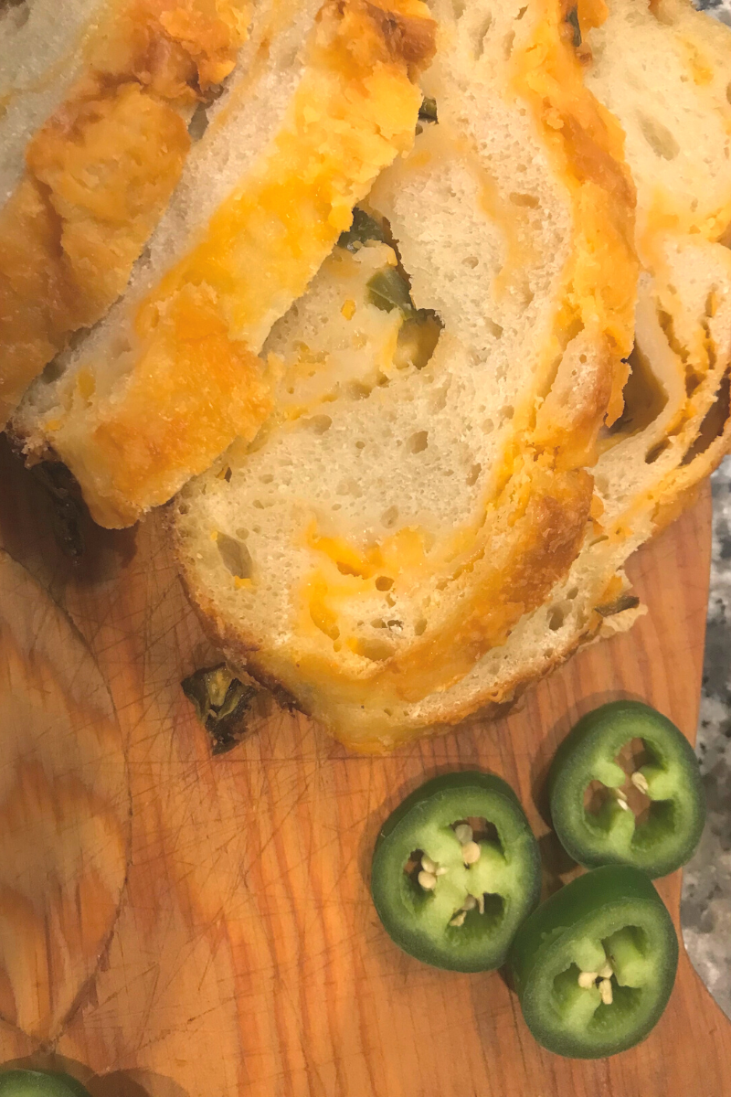 slices of jalapeño cheddar sourdough bread with sliced jalapeños on a cutting board